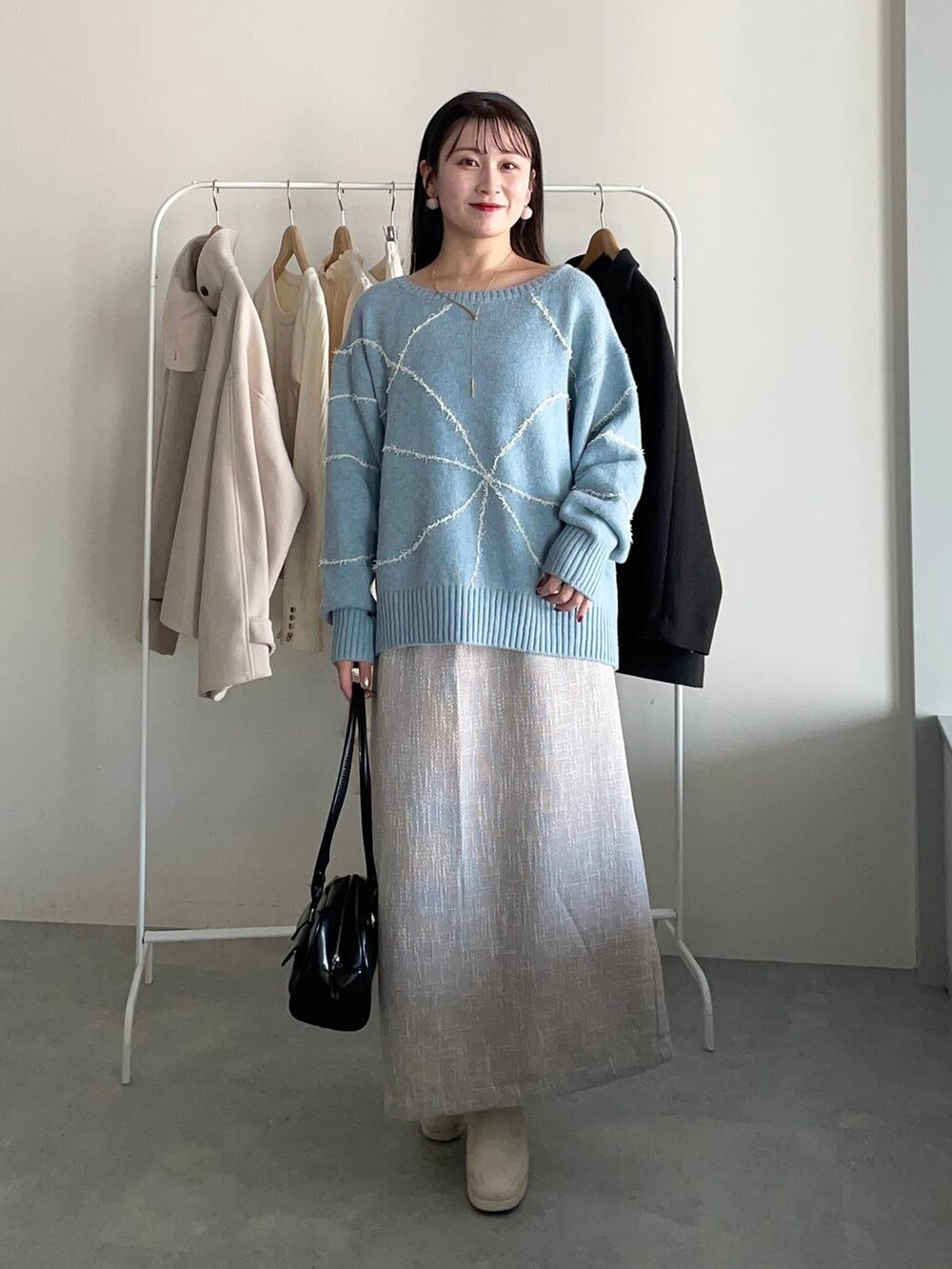 ブラック系のその他アウター、ホワイト系のブーツ、ブラック系のハンドバッグを着用したレディースの冬コーディネートの3枚目の写真