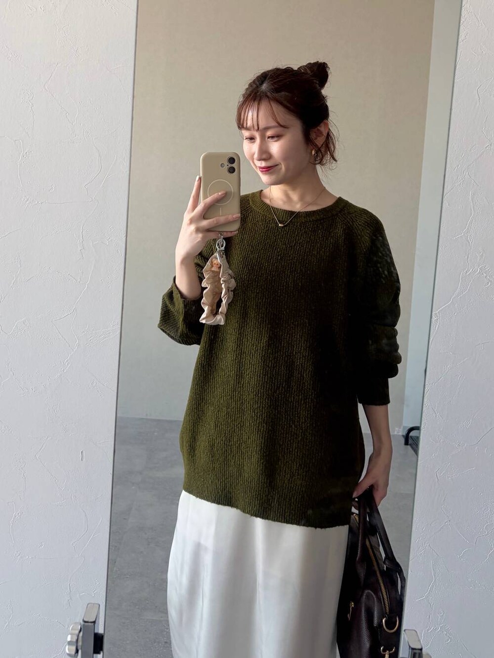 ブラウン系のボストンバッグ、ブルー系のデニムパンツ、グリーン系のニット/セーターを着用したレディースの冬コーディネートの3枚目の写真