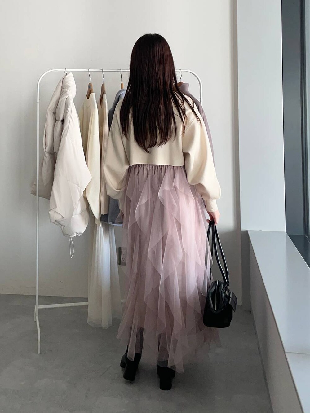 ブラウン系のチェスターコート、ブラック系のブーツ、ホワイト系のワンピースを着用したレディースの冬コーディネートの4枚目の写真