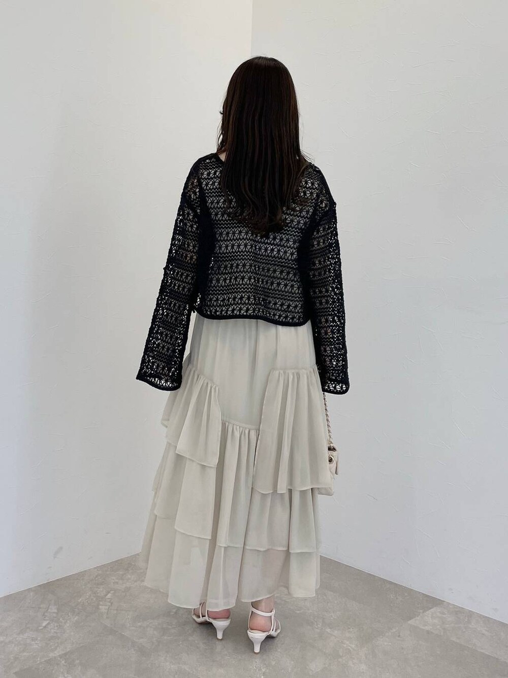 ホワイト系のスカート、ブラック系のカーディガン/ボレロ、ホワイト系のショルダーバッグを着用したレディースの春コーディネートの2枚目の写真