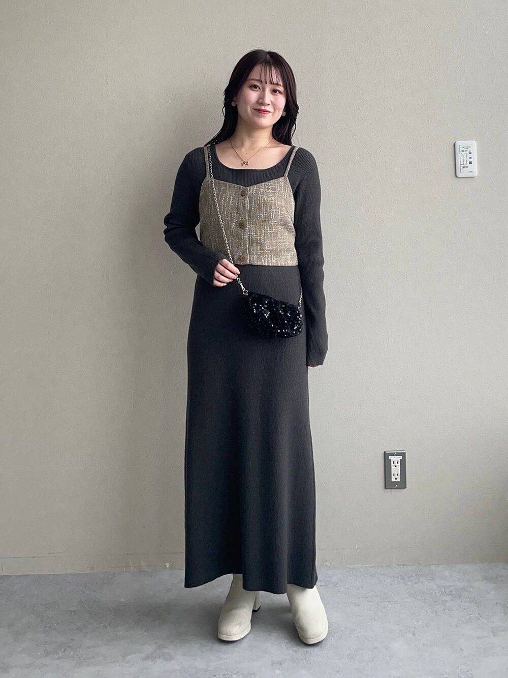 ブラック系のチェスターコート、ホワイト系のブーツ、グレー系のワンピースを着用したレディースの秋コーディネートの3枚目の写真