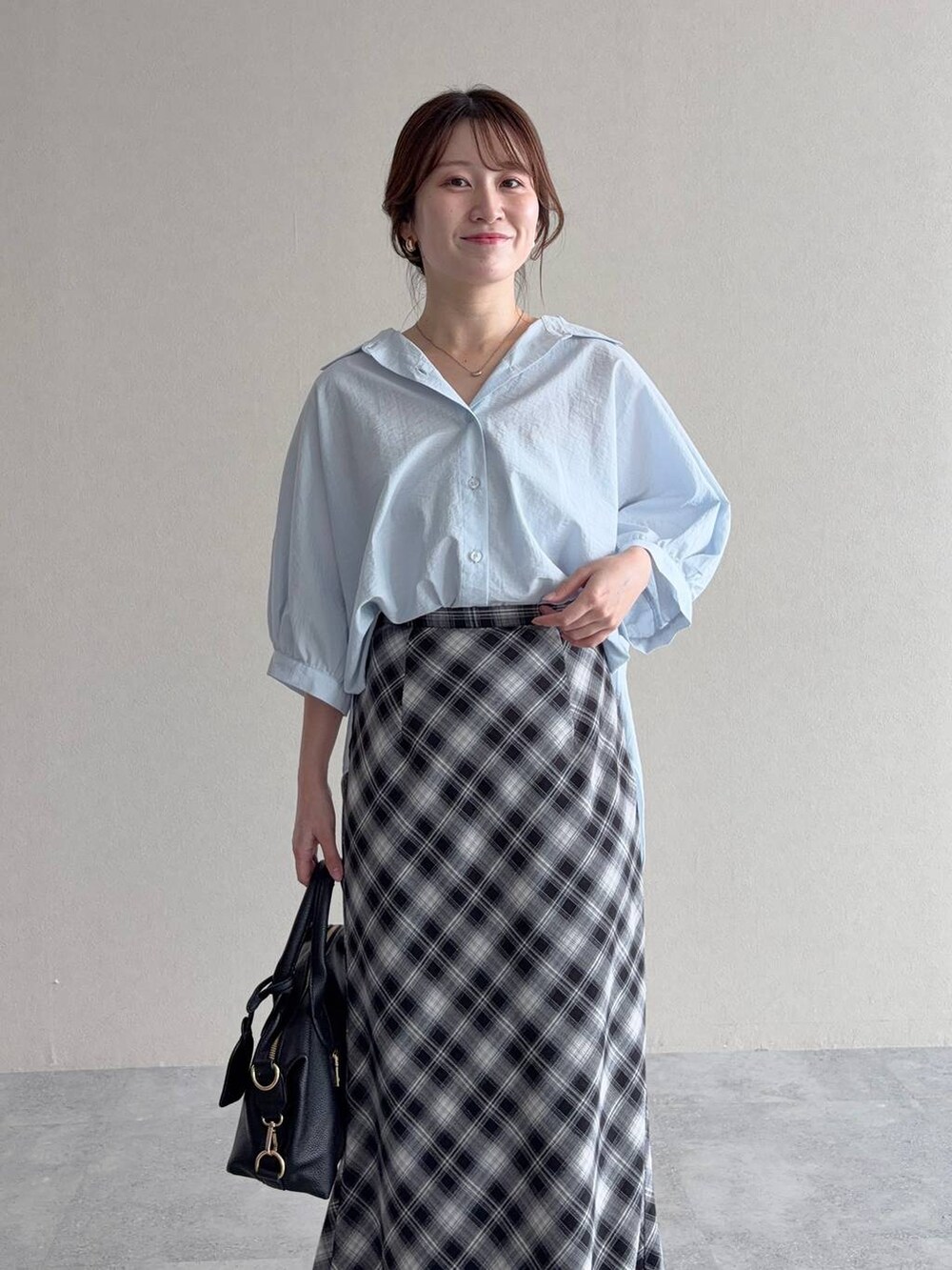 ブルー系のシャツ/ブラウス、グレー系のスカート、ブラック系のボストンバッグを着用したレディースの夏コーディネートの3枚目の写真