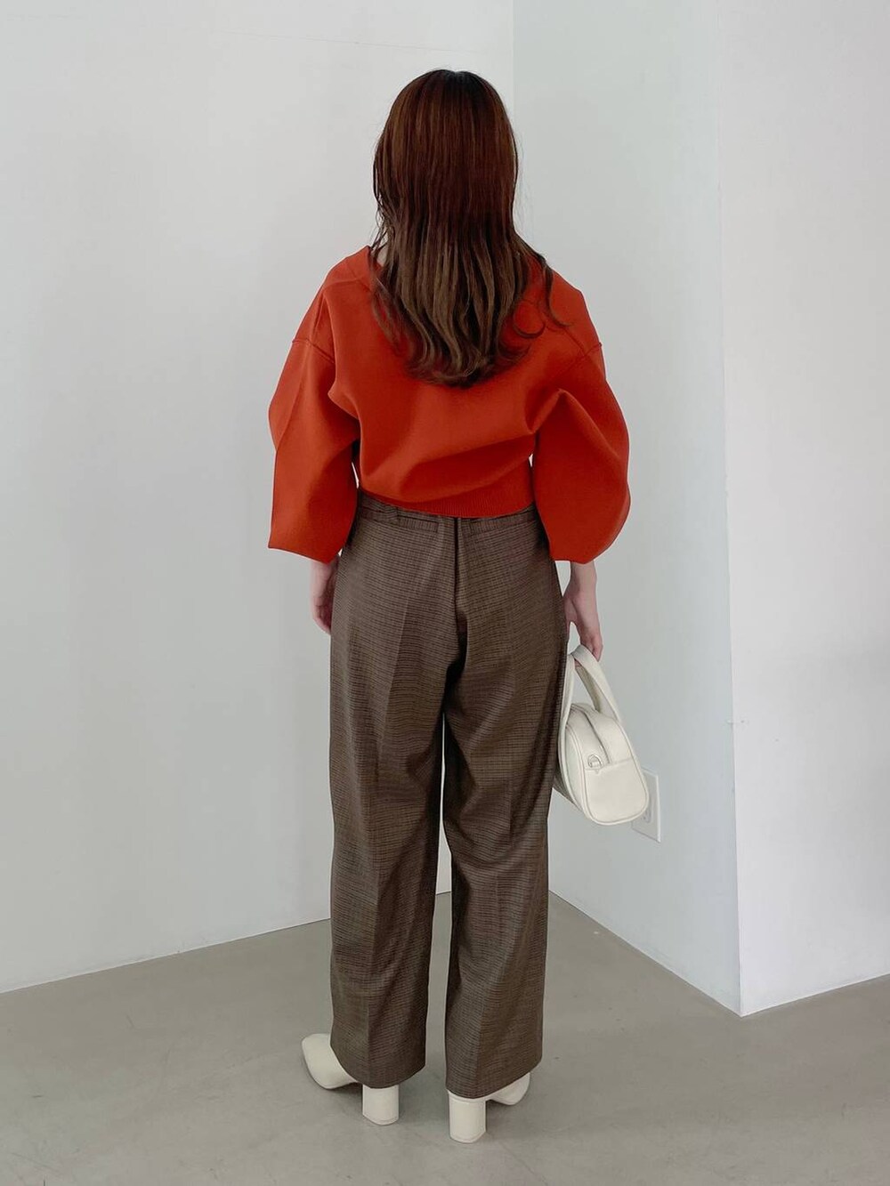 ホワイト系のボストンバッグ、ホワイト系のブーツ、ブラウン系のその他パンツを着用したレディースの秋コーディネートの2枚目の写真