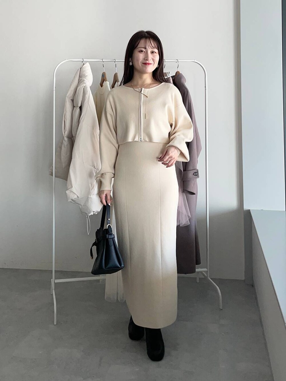 ブラック系のショルダーバッグ、ブラック系のブーツ、ホワイト系のワンピースを着用したレディースの冬コーディネートの4枚目の写真