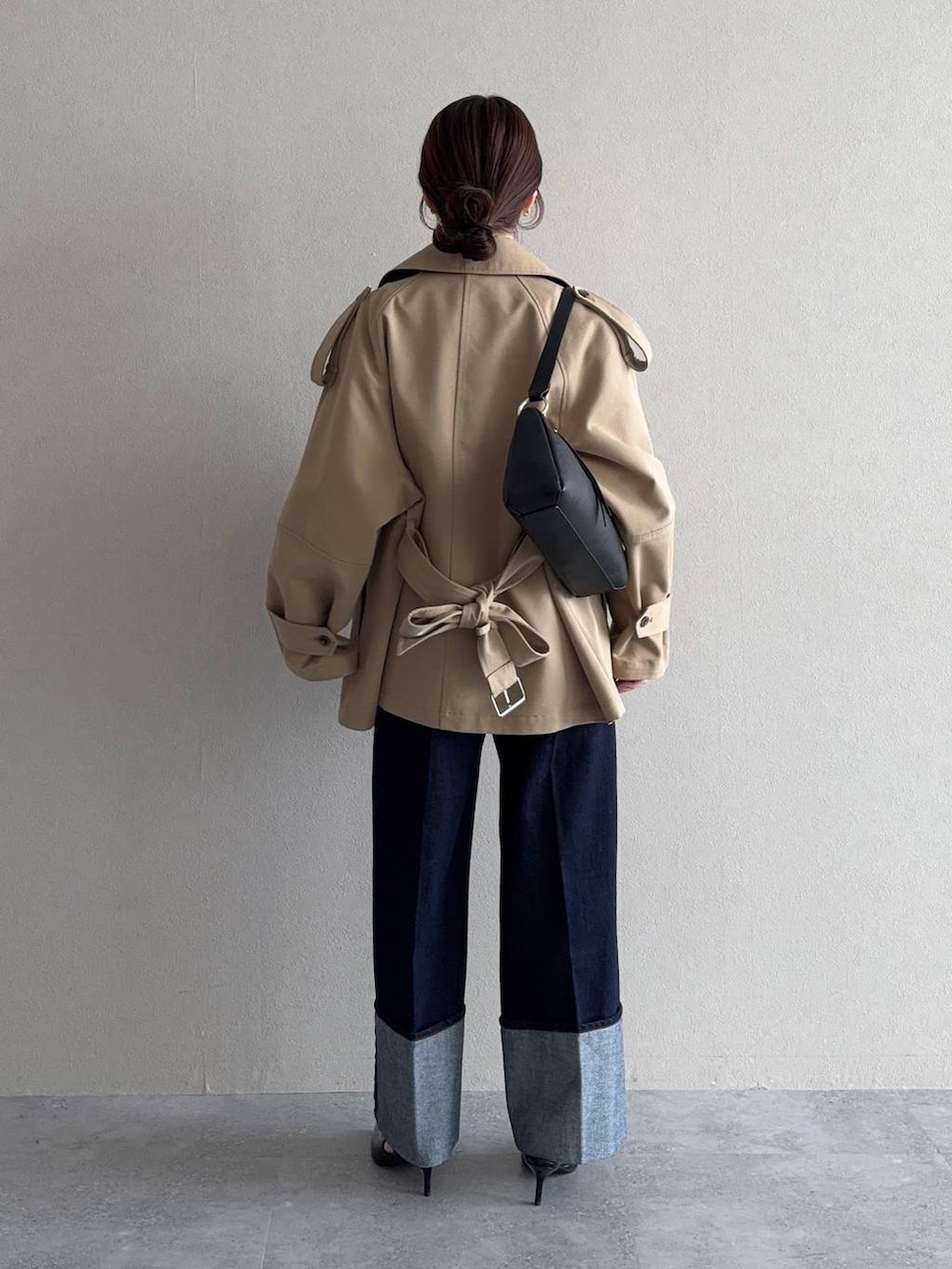 ベージュ系のトレンチコート、ブラック系のサンダル、ブルー系のデニムパンツを着用したレディースの冬コーディネートの2枚目の写真