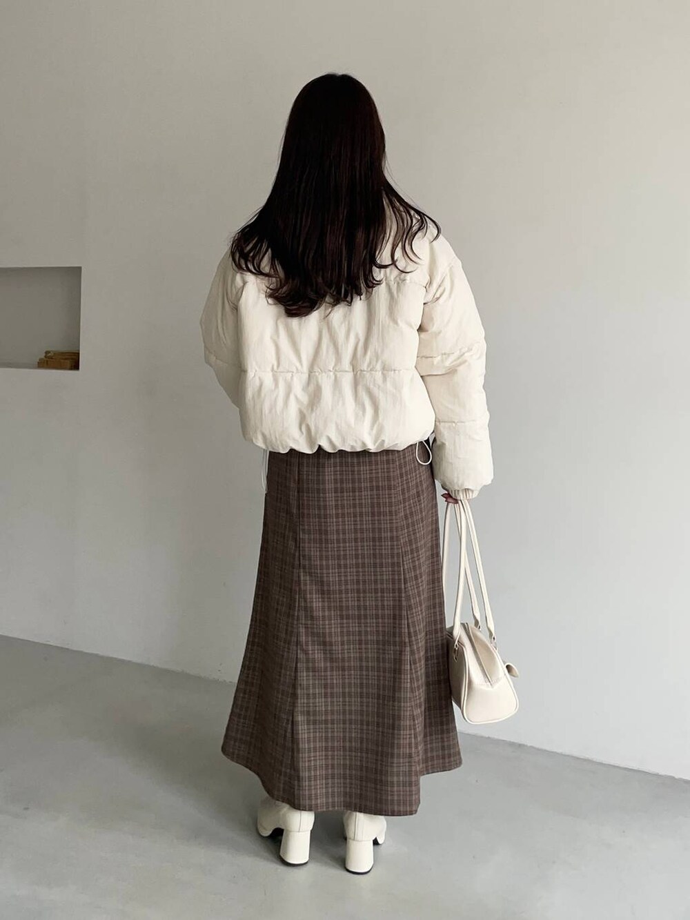 ホワイト系のブルゾン、ホワイト系のブーツ、ブラウン系のスカートを着用したレディースの冬コーディネートの2枚目の写真