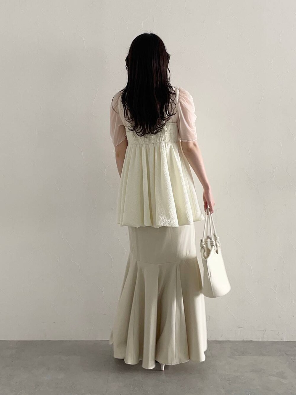 ホワイト系のハンドバッグ、ホワイト系のスカート、ホワイト系のサンダルを着用したレディースの春コーディネートの2枚目の写真