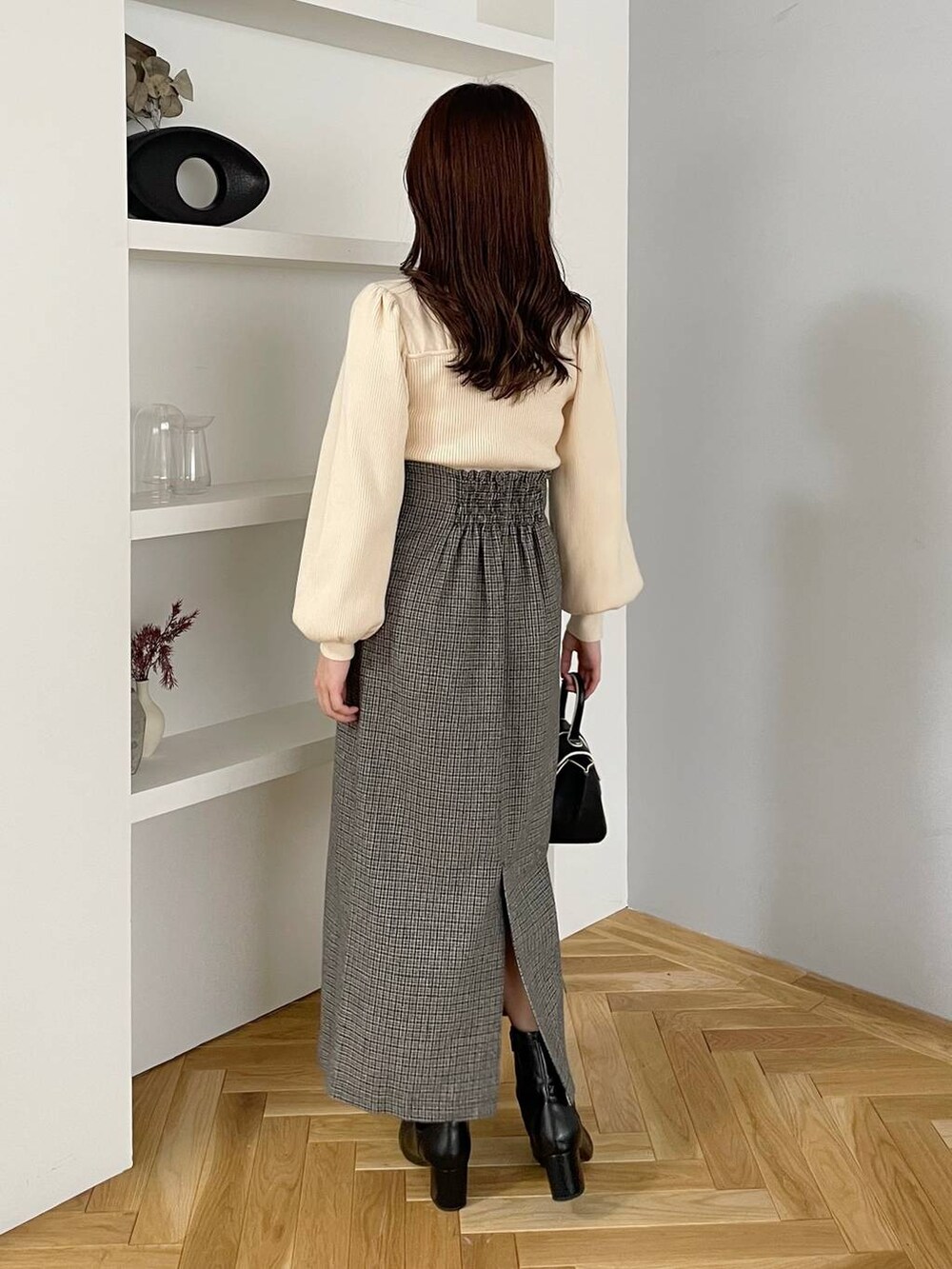 ブラウン系のチェスターコート、ブラック系のハンドバッグ、ブラック系のブーツを着用したレディースの秋コーディネートの4枚目の写真