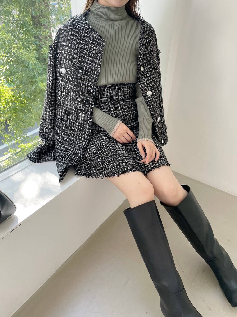 ブラック系のハンドバッグ、ブラック系のブーツ、ブラック系のノーカラージャケットを着用したレディースの秋コーディネートの7枚目の写真