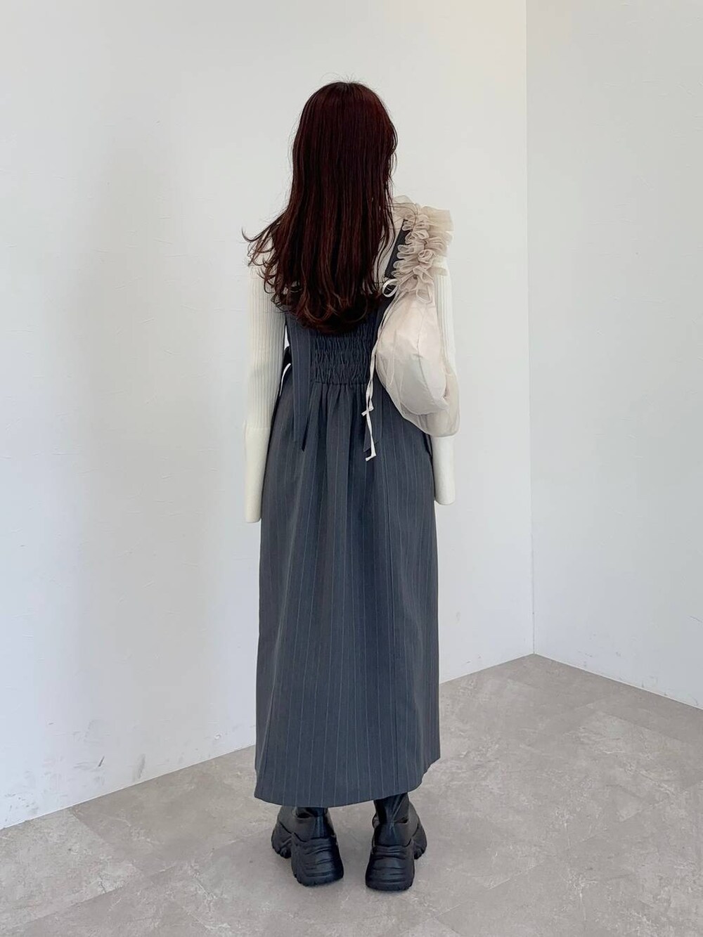 ブラック系のブーツ、ベージュ系のショルダーバッグ、グレー系のジャンパースカートを着用したレディースの冬コーディネートの2枚目の写真