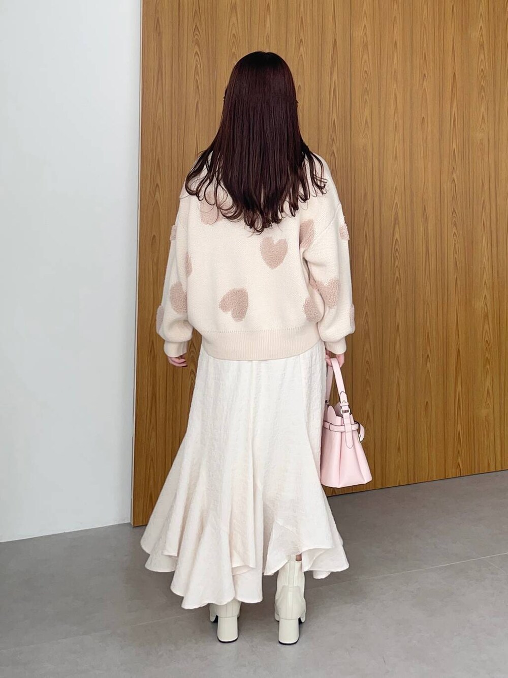 ピンク系のショルダーバッグ、ホワイト系のブーツ、ホワイト系のスカートを着用したレディースの冬コーディネートの2枚目の写真