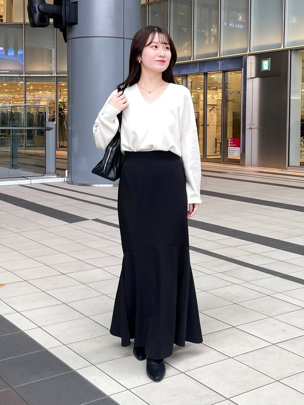 ホワイト系のニット/セーター、ホワイト系のチェスターコート、ブラック系のブーツを着用したレディースの秋コーディネートの5枚目の写真