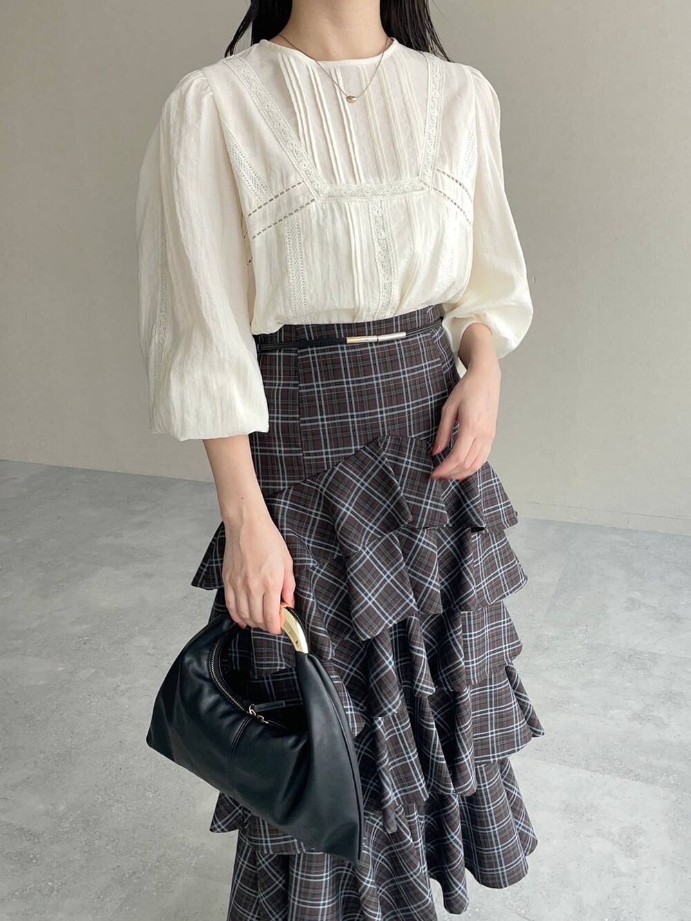 ブラック系のハンドバッグ、ホワイト系のTシャツ/カットソー、ブラウン系のスカートを着用したレディースの秋コーディネートの3枚目の写真