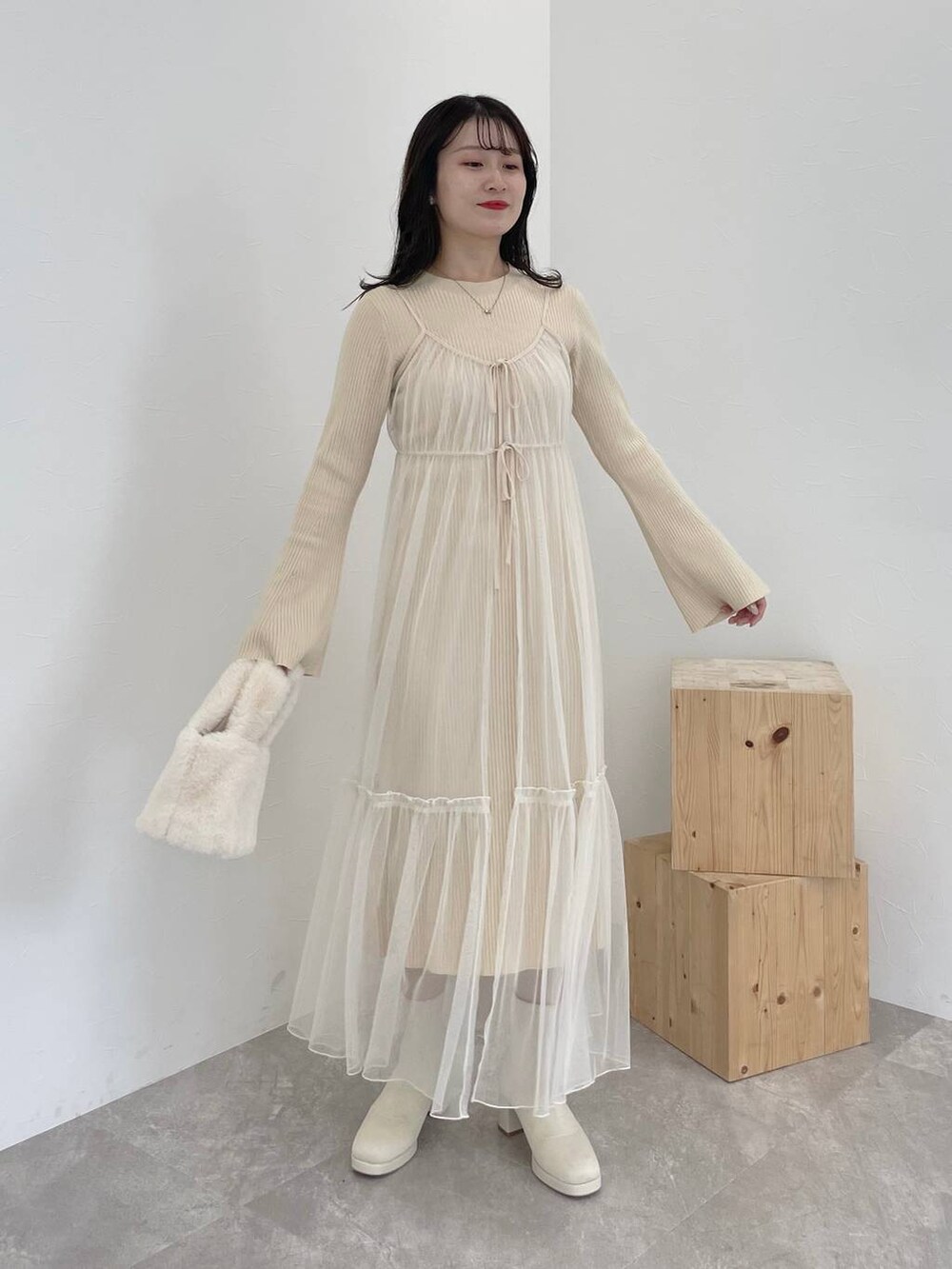 ホワイト系のブーツ、ホワイト系のハンドバッグ、ブラウン系のチェスターコートを着用したレディースの秋コーディネートの5枚目の写真