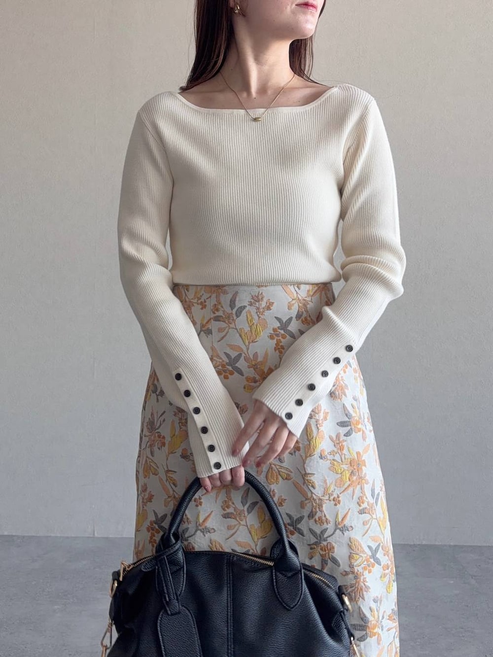 ブラック系のボストンバッグ、ホワイト系のスカート、ブラック系のパンプスを着用したレディースの冬コーディネートの3枚目の写真