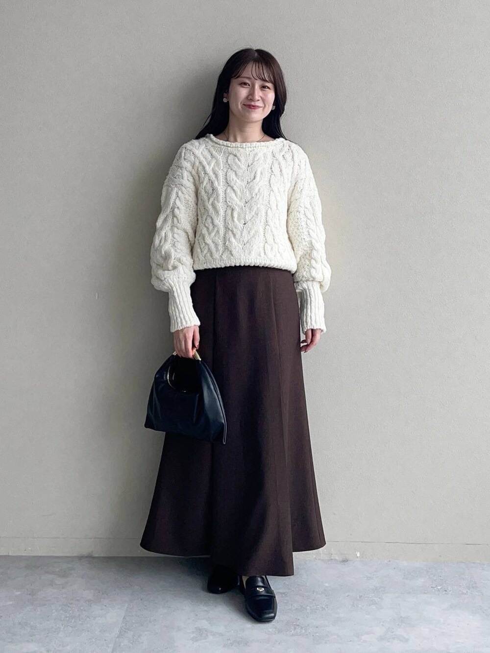 ベージュ系のチェスターコート、ブラック系のハンドバッグ、ブラウン系のスカートを着用したレディースの秋コーディネートの3枚目の写真