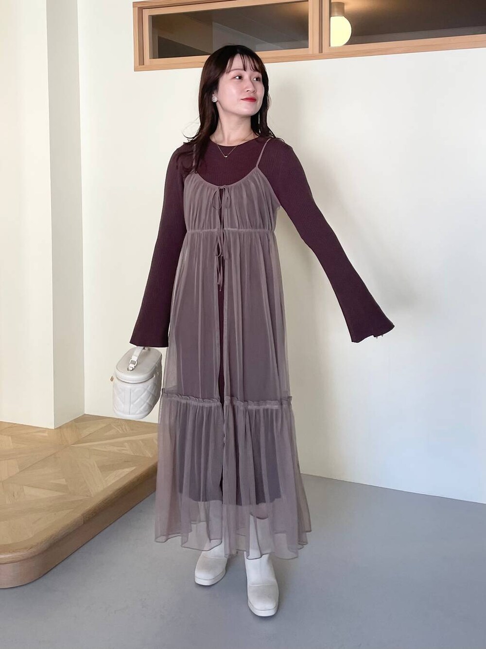 ホワイト系のチェスターコート、ホワイト系のブーツ、ホワイト系のショルダーバッグを着用したレディースの冬コーディネートの4枚目の写真