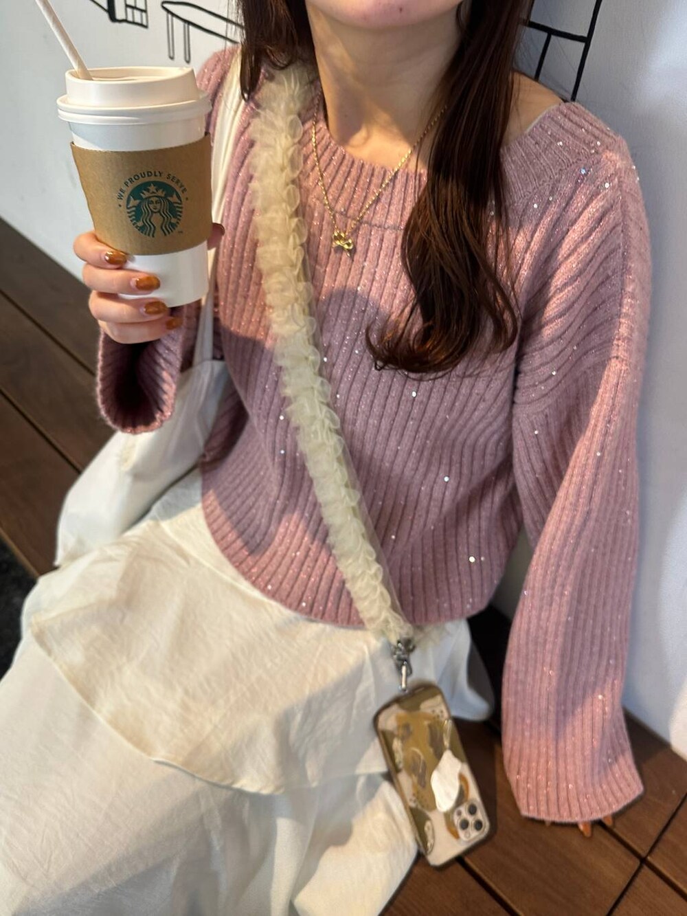 ホワイト系のスカート、ピンク系のニット/セーター、ベージュ系のスマホグッズを着用したレディースの秋コーディネートの4枚目の写真