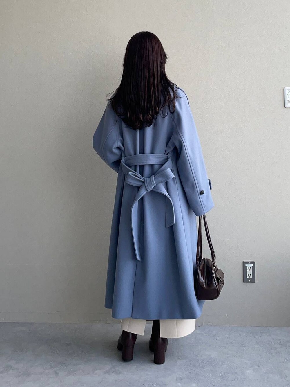 ブルー系のチェスターコート、ブラウン系のブーツ、ホワイト系のワンピースを着用したレディースの冬コーディネートの2枚目の写真