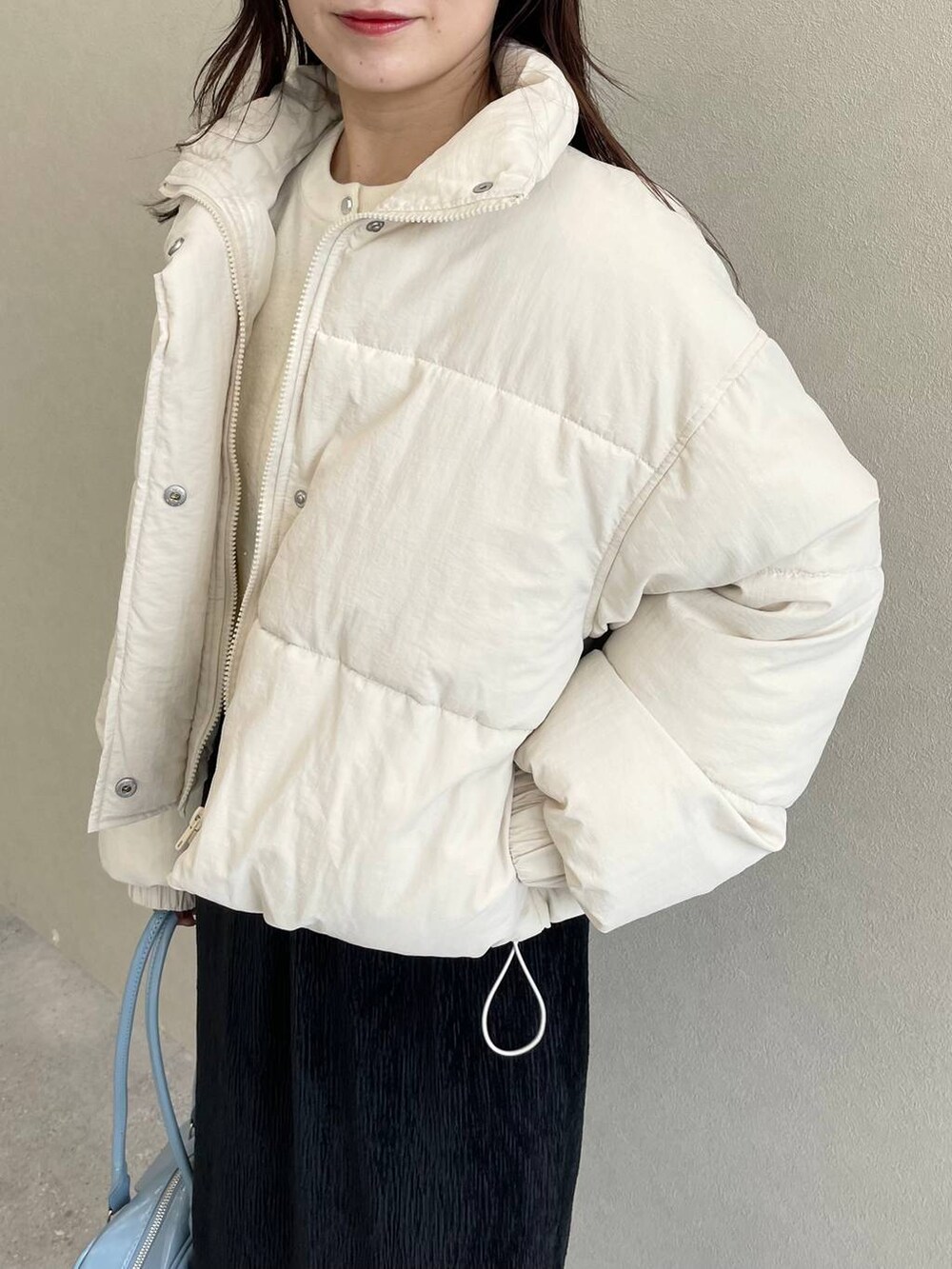 ホワイト系のブルゾン、ホワイト系のブーツ、ブラック系のスカートを着用したレディースの秋コーディネートの4枚目の写真