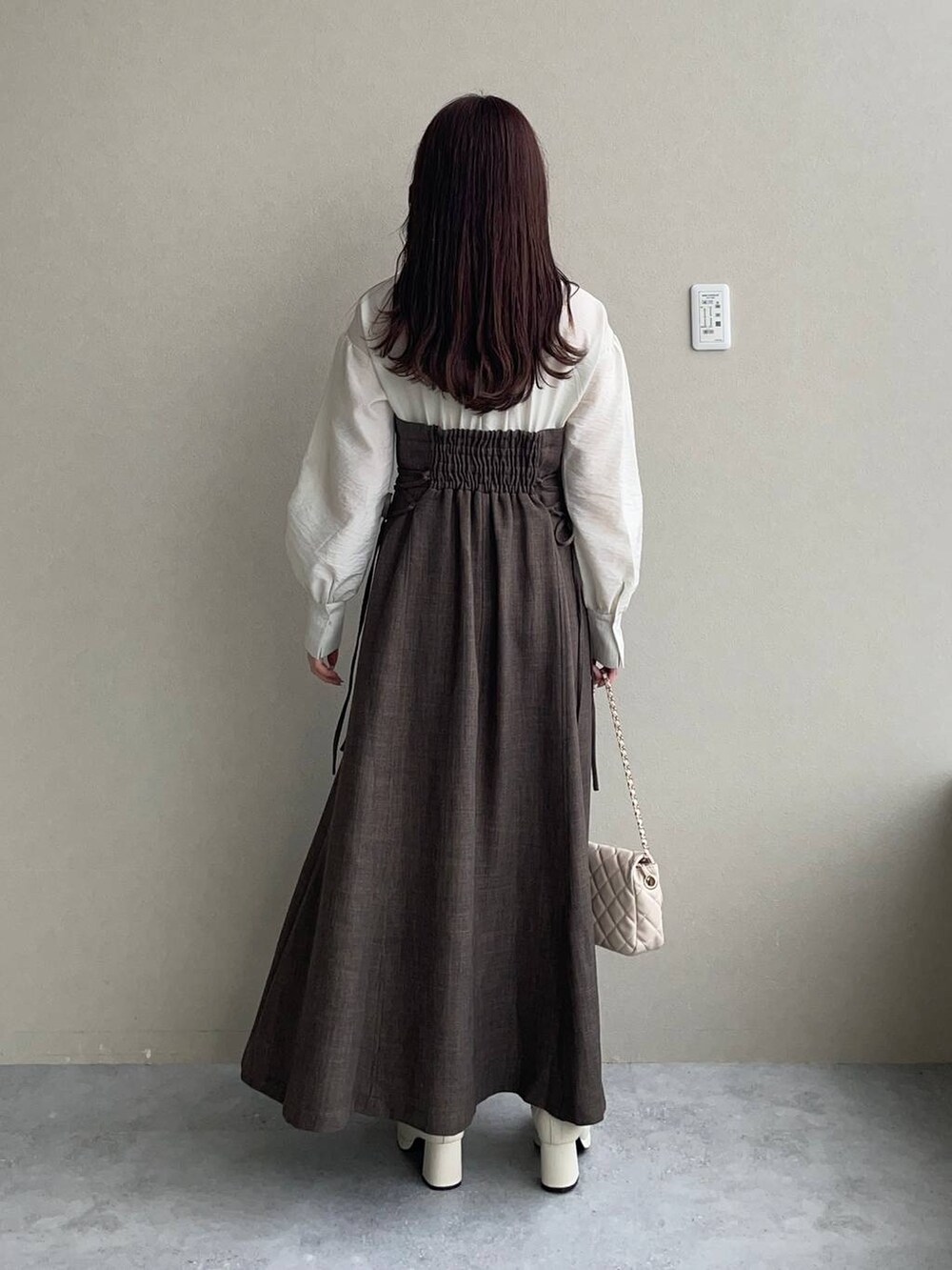 ホワイト系のブーツ、ブラウン系のワンピース、ホワイト系のショルダーバッグを着用したレディースの秋コーディネートの2枚目の写真