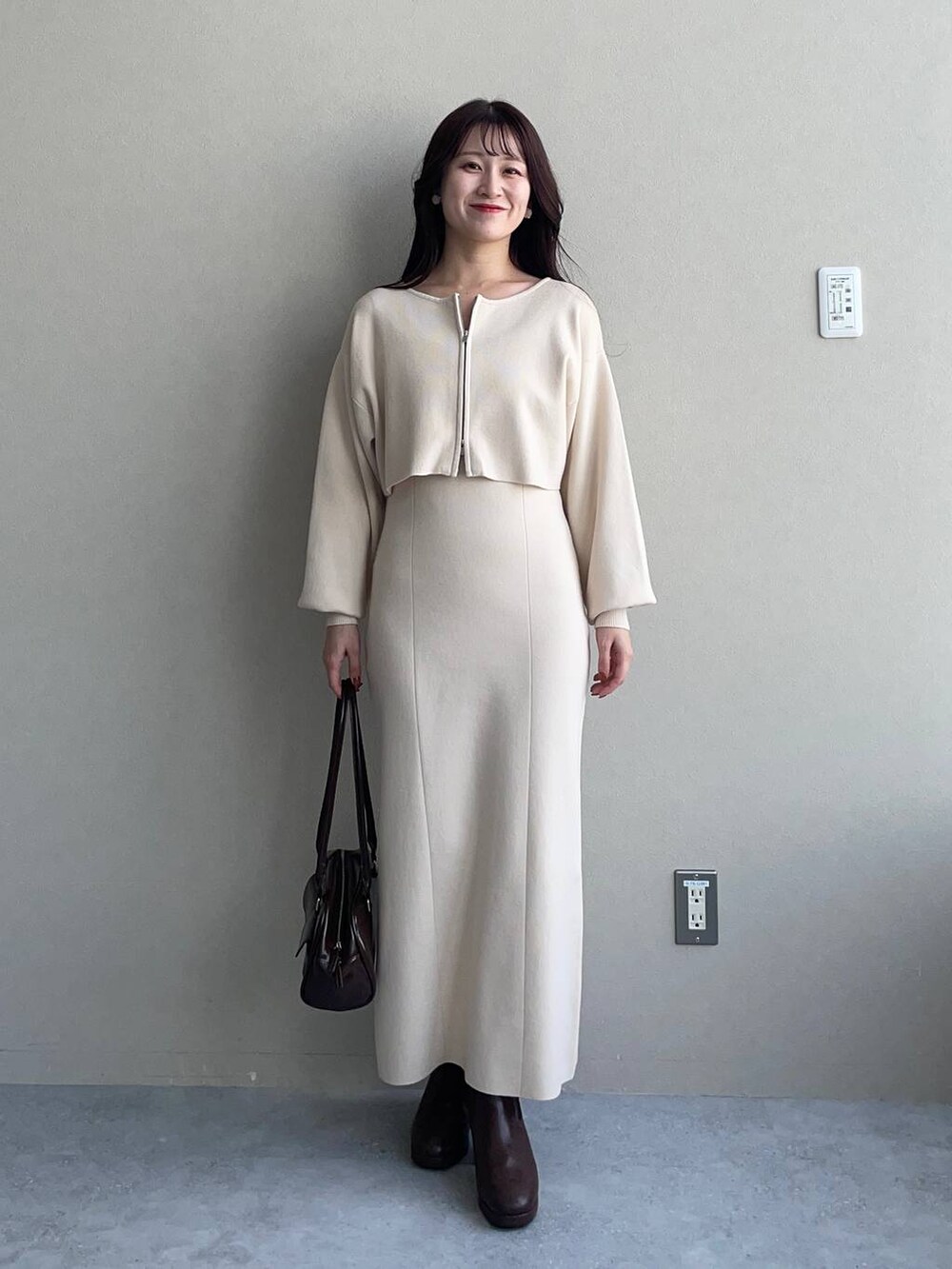 ブルー系のチェスターコート、ブラウン系のブーツ、ホワイト系のワンピースを着用したレディースの冬コーディネートの3枚目の写真