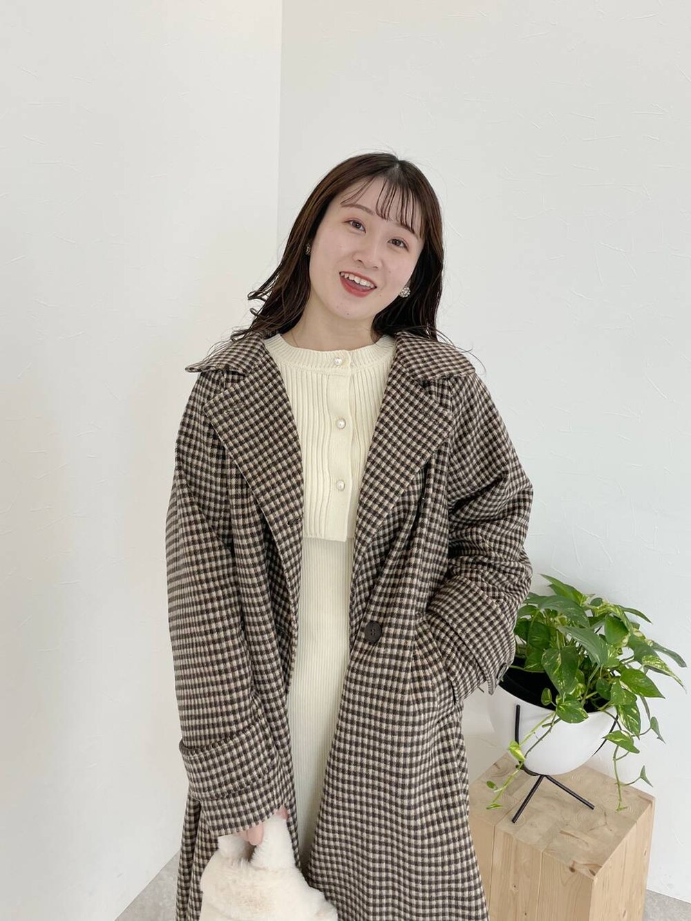 ホワイト系のブーツ、ホワイト系のハンドバッグ、ブラウン系のチェスターコートを着用したレディースの秋コーディネートの4枚目の写真