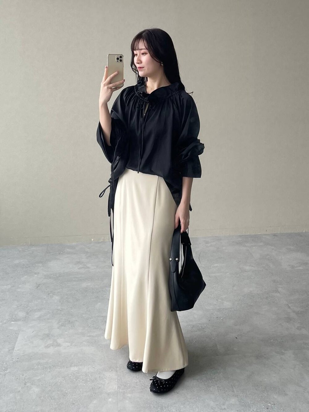 ベージュ系のスカート、ブラック系のバレエシューズ、ブラック系のショルダーバッグを着用したレディースの春コーディネートの3枚目の写真