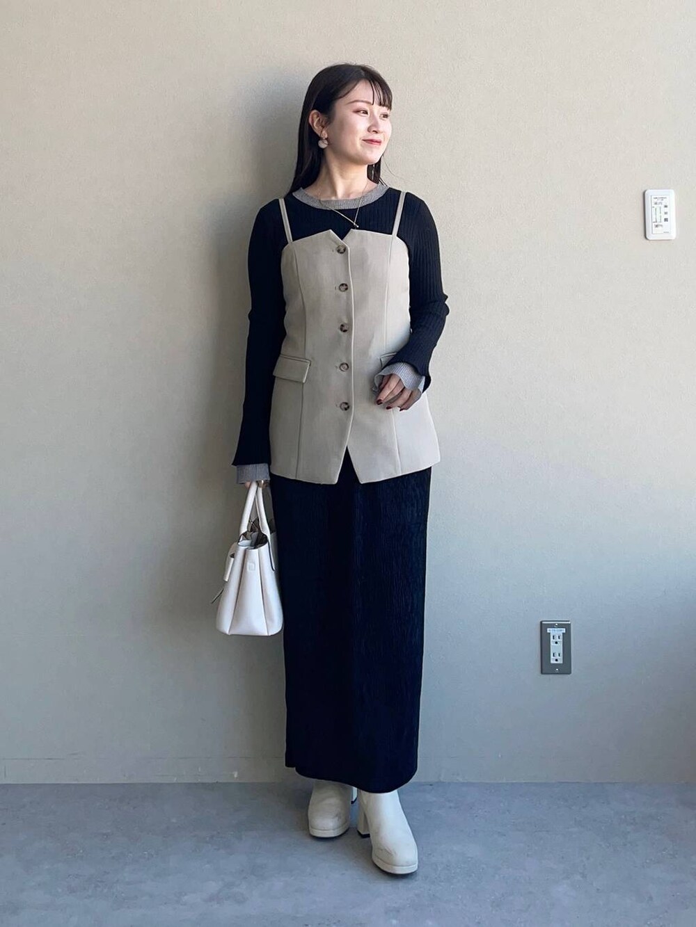 ホワイト系のブーツ、ブラック系のスカート、ホワイト系のショルダーバッグを着用したレディースの冬コーディネートの5枚目の写真