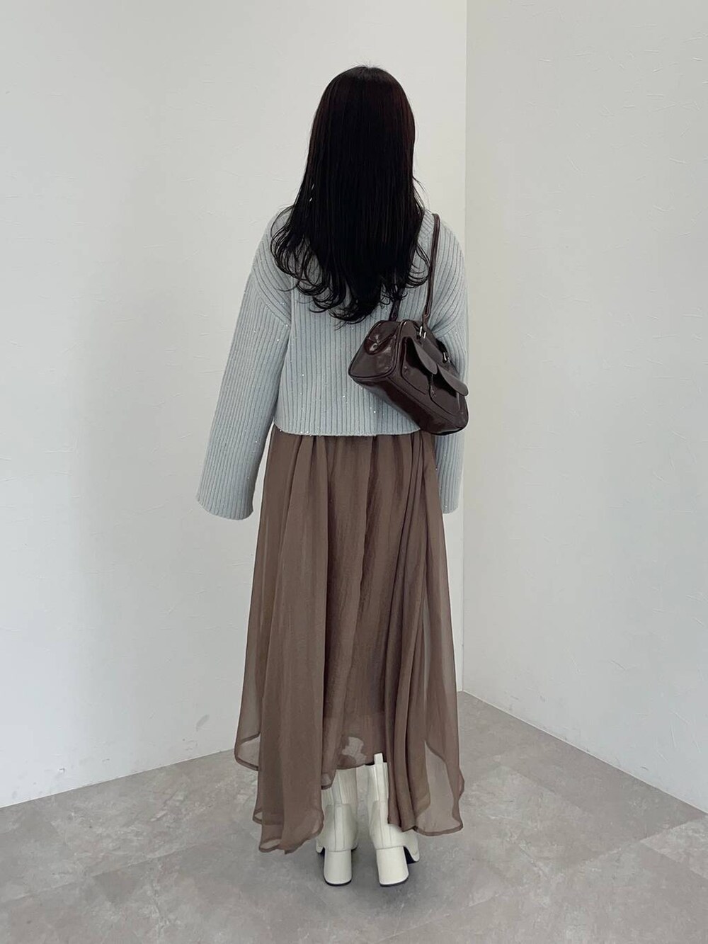 ホワイト系のブーツ、ブラウン系のハンドバッグ、ブラウン系のスカートを着用したレディースの冬コーディネートの2枚目の写真
