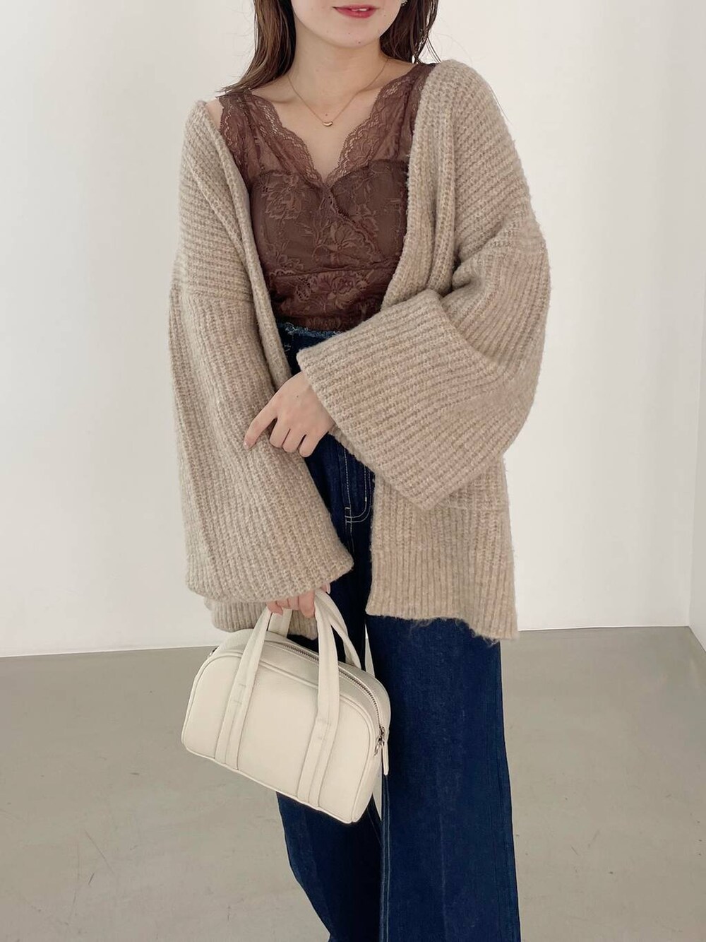 ブルー系のデニムパンツ、ホワイト系のボストンバッグ、ホワイト系のパンプスを着用したレディースの秋コーディネートの3枚目の写真