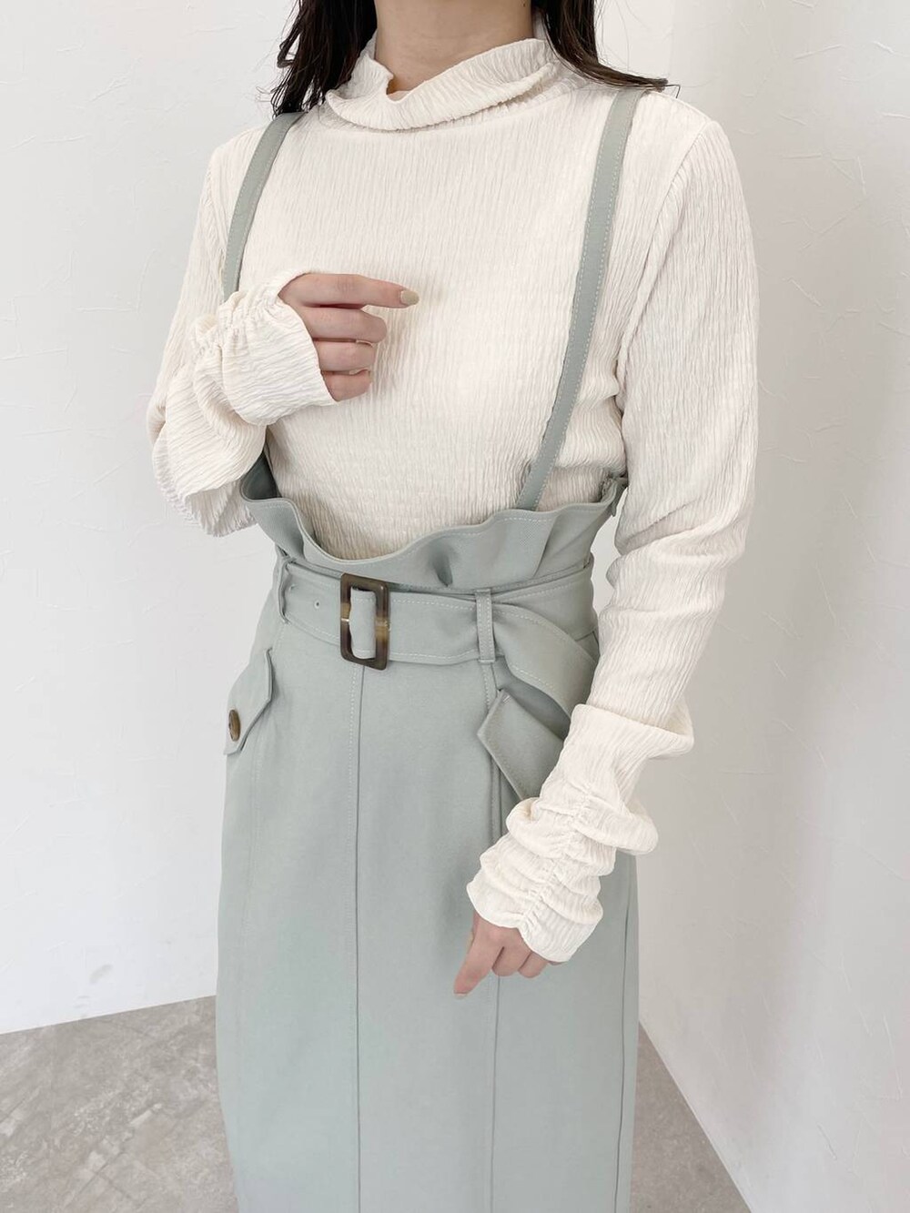 ホワイト系のブーツ、ホワイト系のハンドバッグ、グリーン系のスカートを着用したレディースの冬コーディネートの3枚目の写真