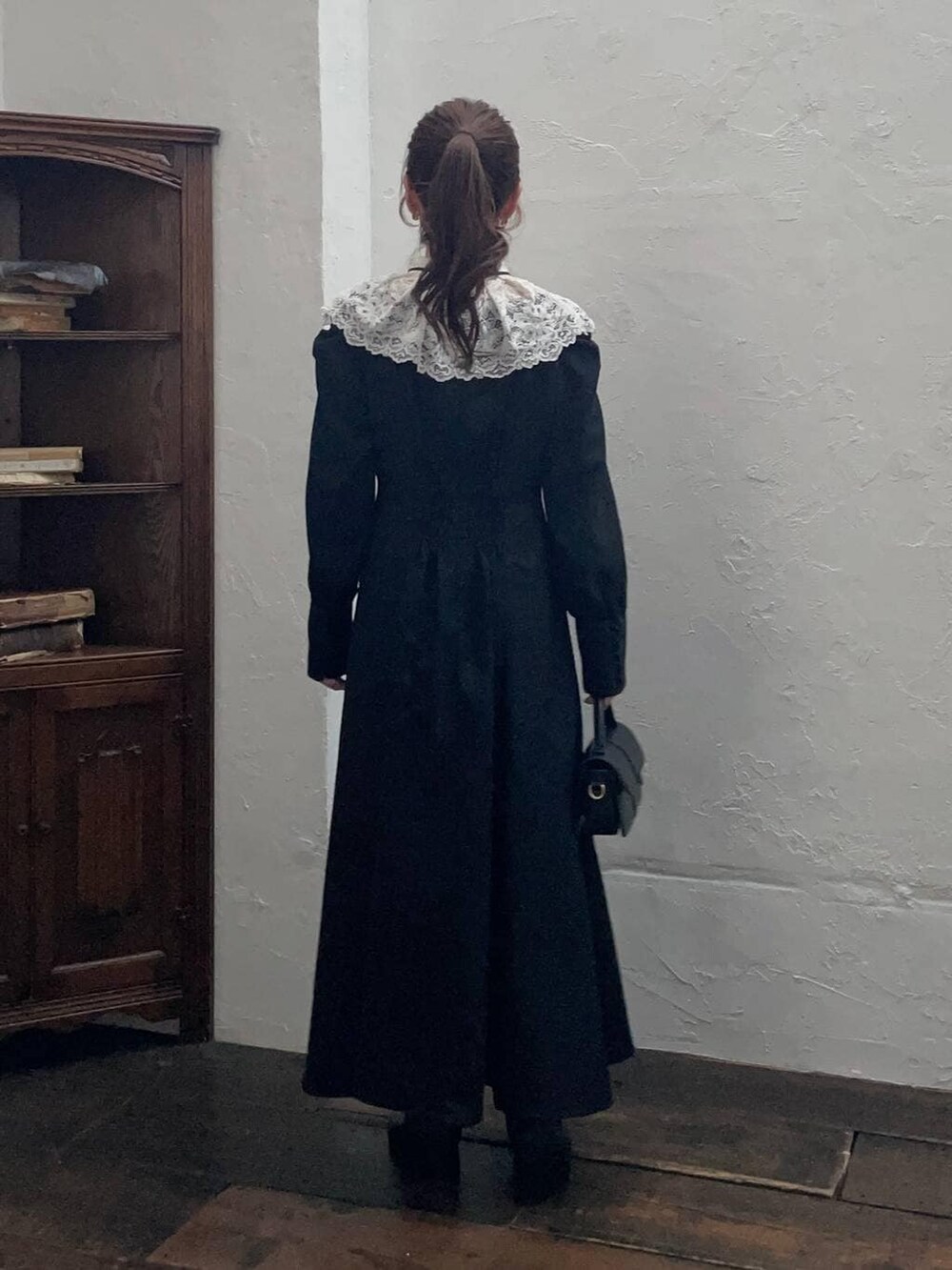 ホワイト系のチェスターコート、ブラック系のブーツ、ブラック系のショルダーバッグを着用したレディースの冬コーディネートの4枚目の写真