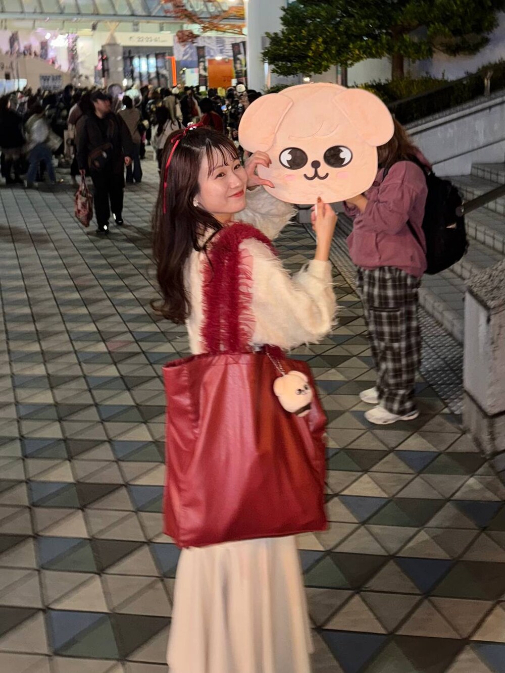 レッド系のトートバッグ、ホワイト系のスカート、ベージュ系のスマホグッズを着用したレディースの秋コーディネートの2枚目の写真