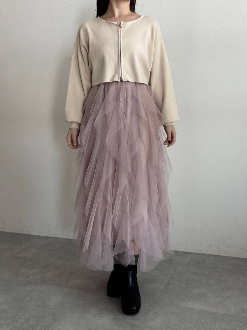 ブラウン系のチェスターコート、ブラック系のブーツ、ホワイト系のワンピースを着用したレディースの冬コーディネートの5枚目の写真