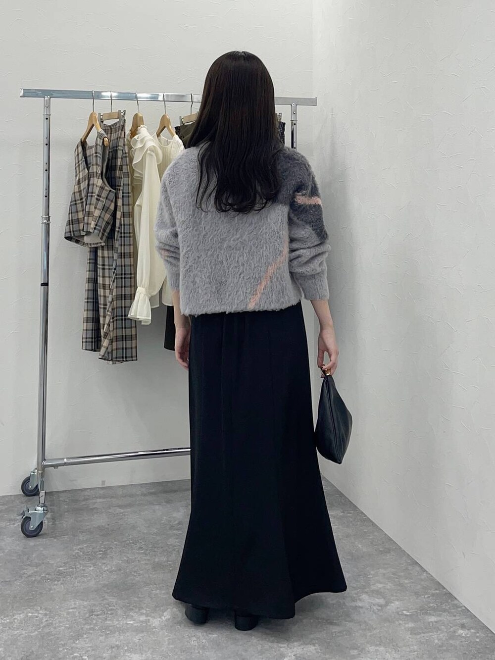 ブラック系のスカート、グレー系のニット/セーター、ブラック系のハンドバッグを着用したレディースの秋コーディネートの2枚目の写真