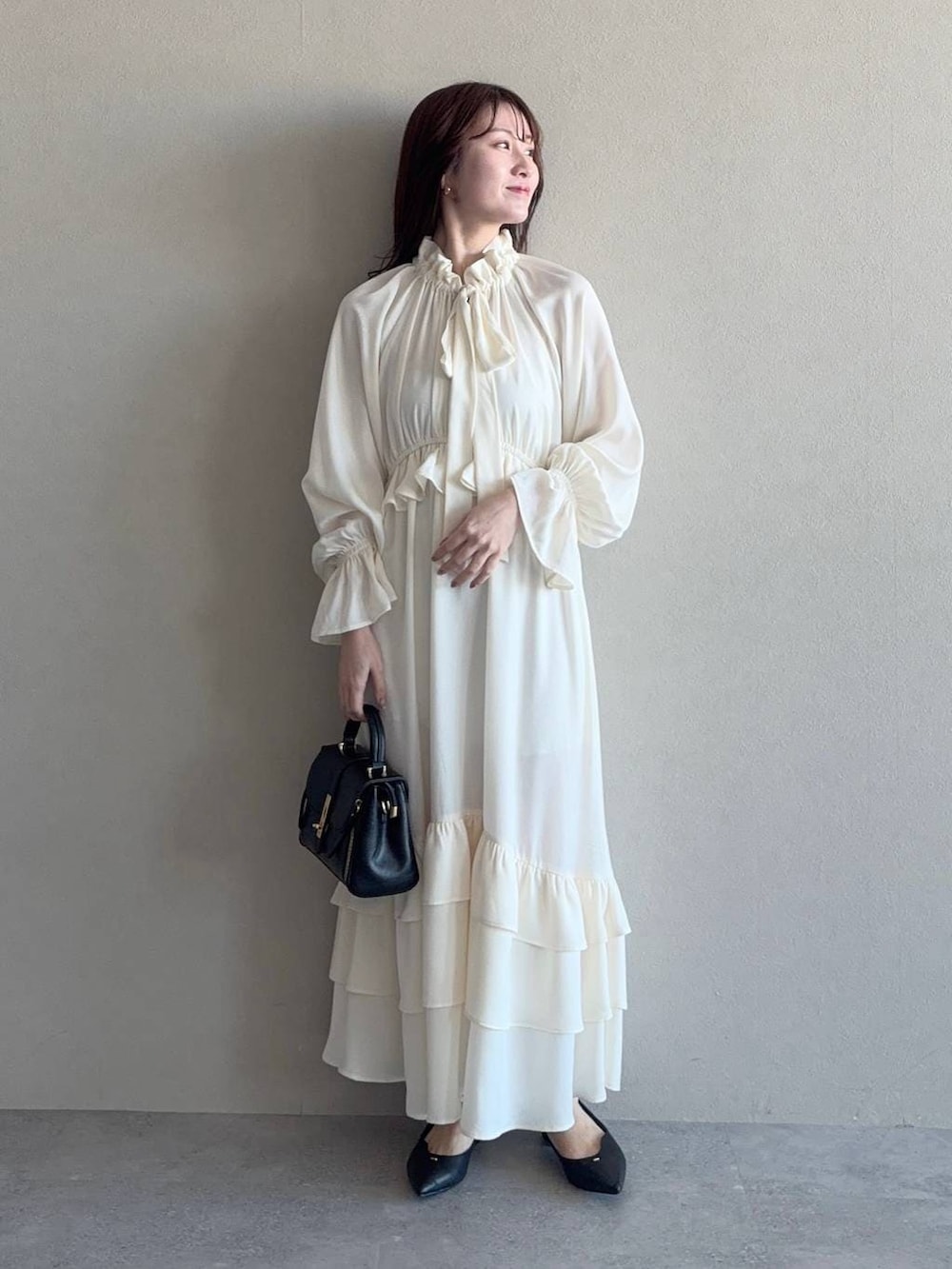 ブラック系のショルダーバッグ、ブラック系のパンプス、ホワイト系のワンピースを着用したレディースの冬コーディネートの4枚目の写真