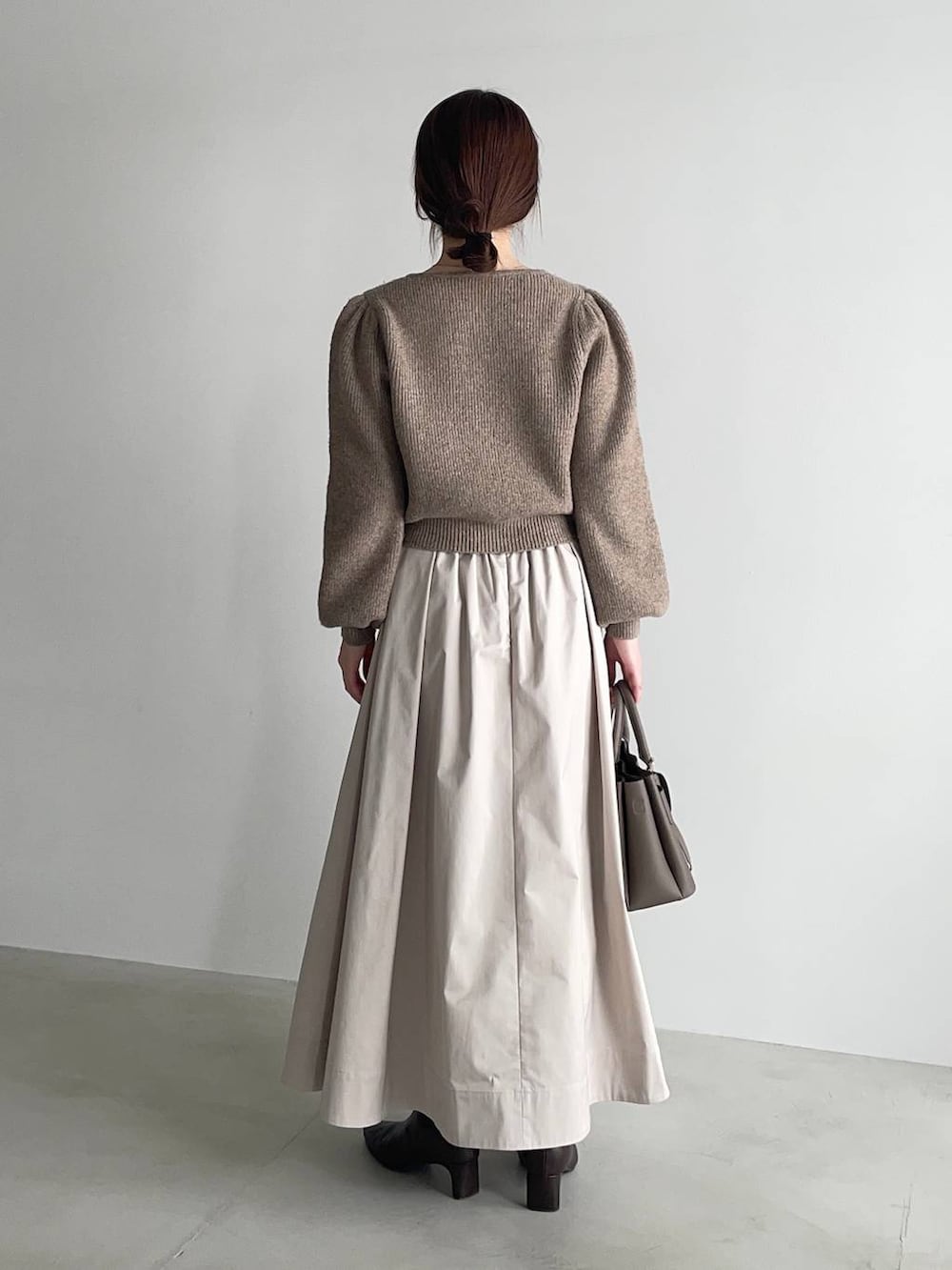 ベージュ系のショルダーバッグ、ブラウン系のブーツ、ベージュ系のワンピースを着用したレディースの冬コーディネートの2枚目の写真