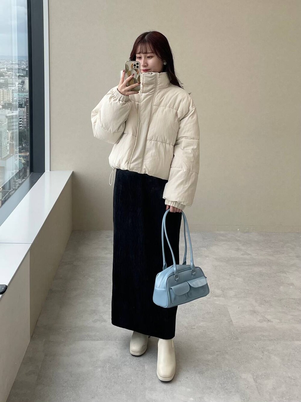 ホワイト系のブルゾン、ホワイト系のブーツ、ブラック系のスカートを着用したレディースの秋コーディネートの5枚目の写真
