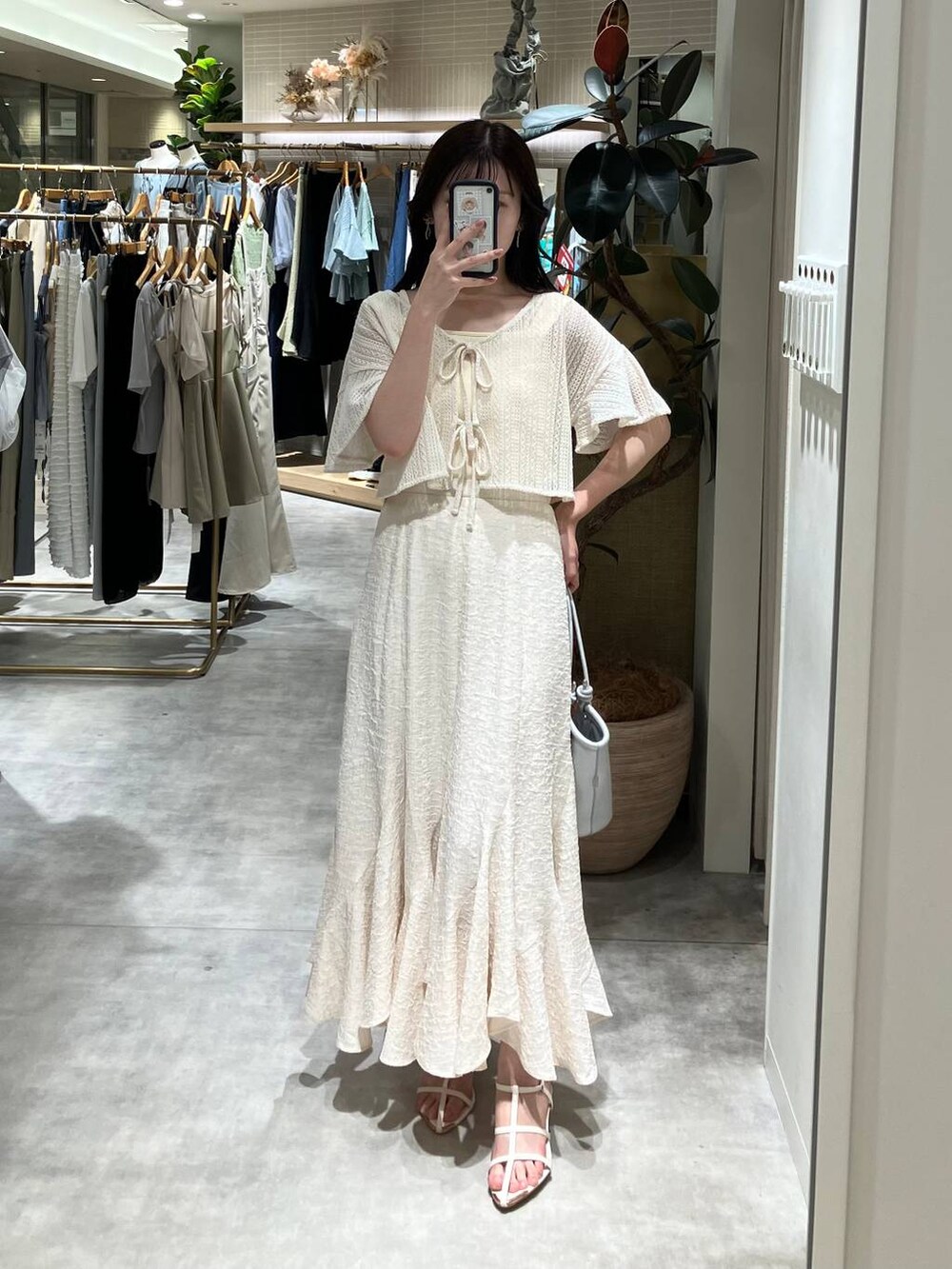 シルバー系のハンドバッグ、ホワイト系のサンダル、ホワイト系のスカートを着用したレディースの春コーディネートの3枚目の写真