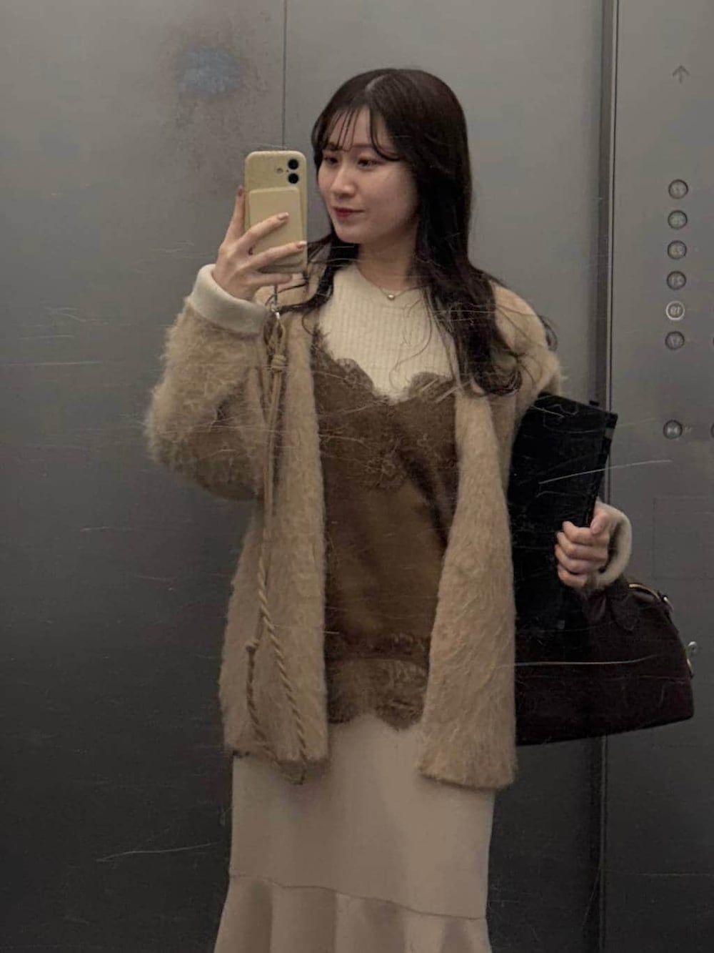 ブラック系のボストンバッグ、ブラウン系のキャミソール、ベージュ系のスマホグッズを着用したレディースの春コーディネートの2枚目の写真