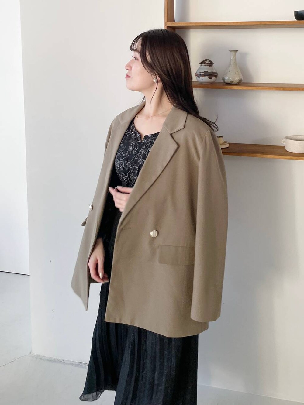 ブラウン系のテーラードジャケット、ブラック系のパンプス、ブラック系のワンピースを着用したレディースの冬コーディネートの2枚目の写真