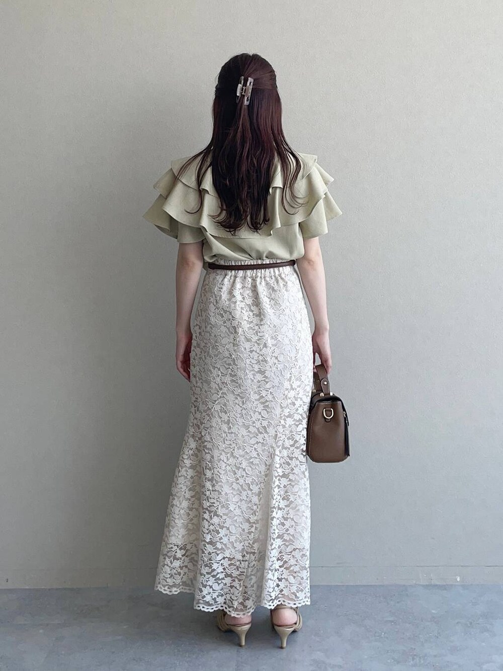 ゴールド系のパンプス、ブラウン系のショルダーバッグ、ベージュ系のスカートを着用したレディースの夏コーディネートの2枚目の写真