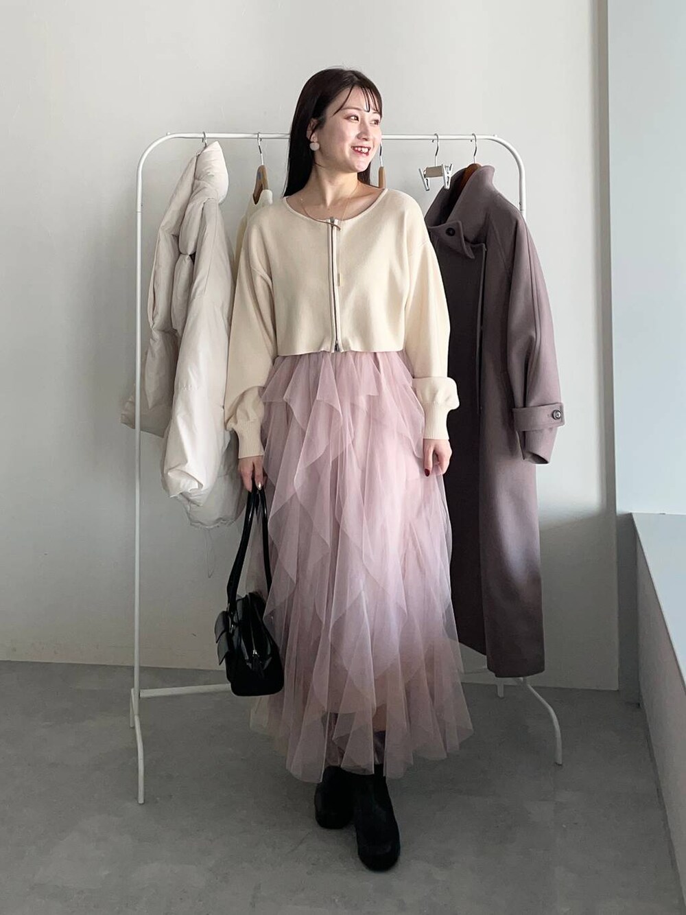 ブラウン系のチェスターコート、ブラック系のブーツ、ホワイト系のワンピースを着用したレディースの冬コーディネートの3枚目の写真