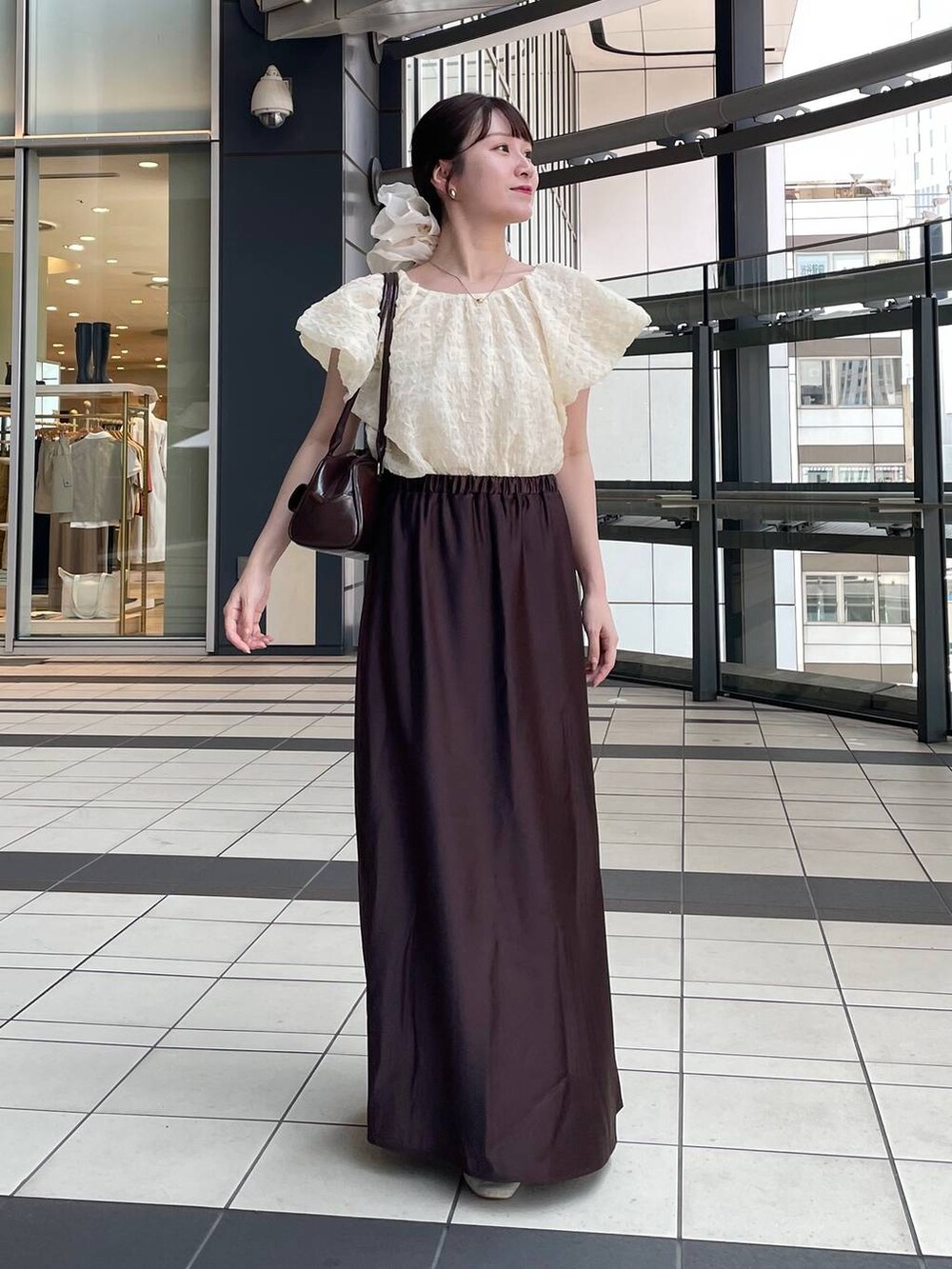 ブラウン系のスカート、ベージュ系のシャツ/ブラウス、ベージュ系のシュシュを着用したレディースの夏コーディネートの2枚目の写真