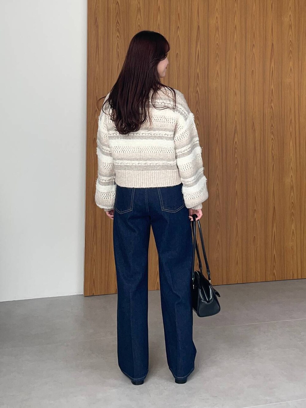 ブラック系のブーツ、ブラック系のハンドバッグ、ブルー系のデニムパンツを着用したレディースの冬コーディネートの2枚目の写真