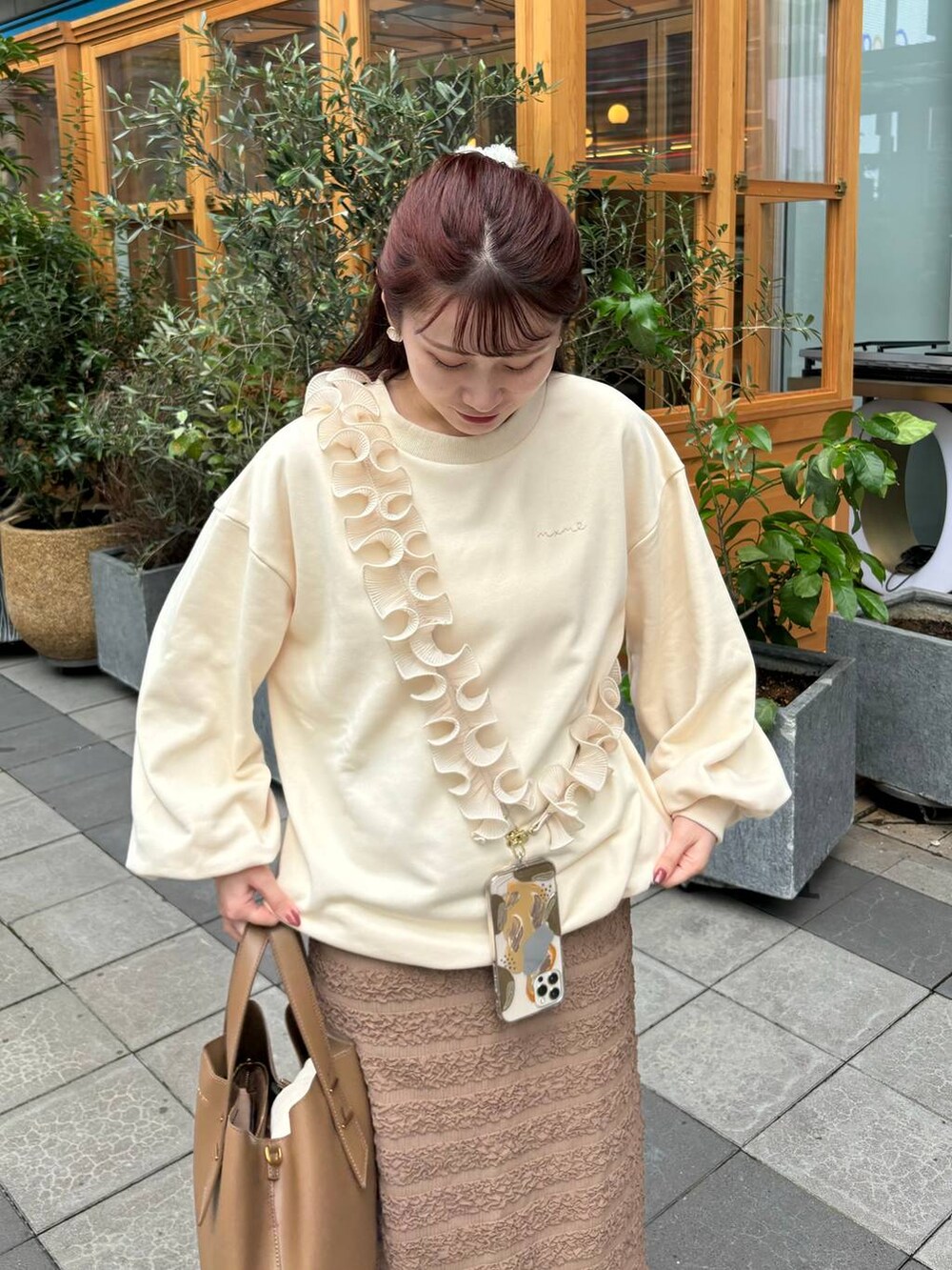 ホワイト系のスウェット、ブラウン系のスカート、ホワイト系のスマホグッズを着用したレディースの秋コーディネートの2枚目の写真