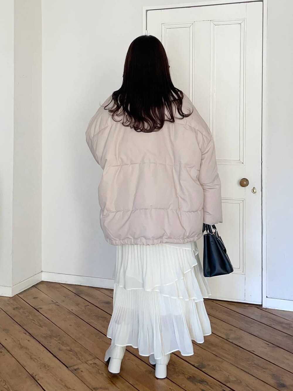 ホワイト系のブーツ、ベージュ系のブルゾン、ブラック系のショルダーバッグを着用したレディースの冬コーディネートの2枚目の写真