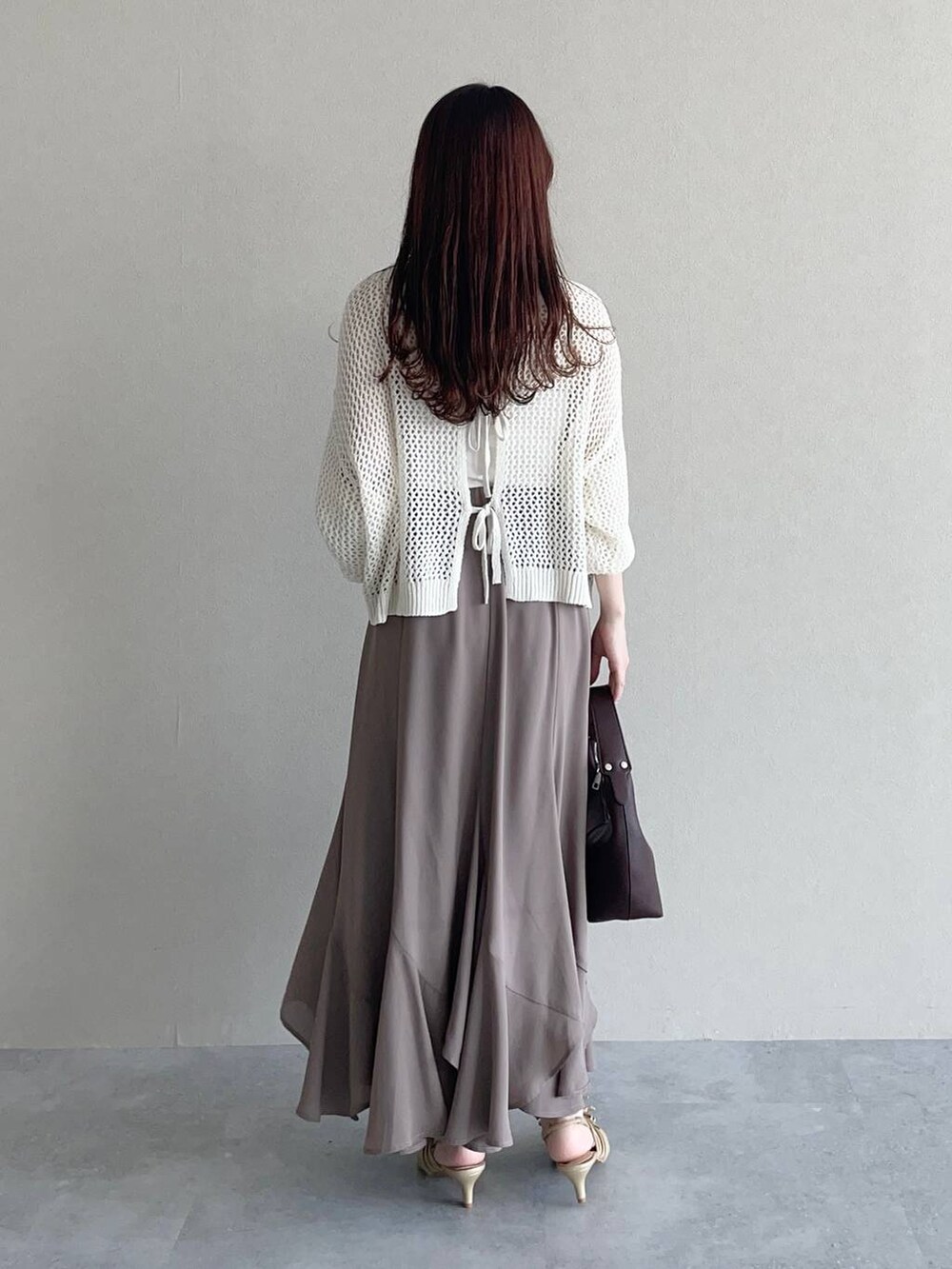 ブラウン系のショルダーバッグ、ゴールド系のパンプス、ホワイト系のニット/セーターを着用したレディースの春コーディネートの2枚目の写真