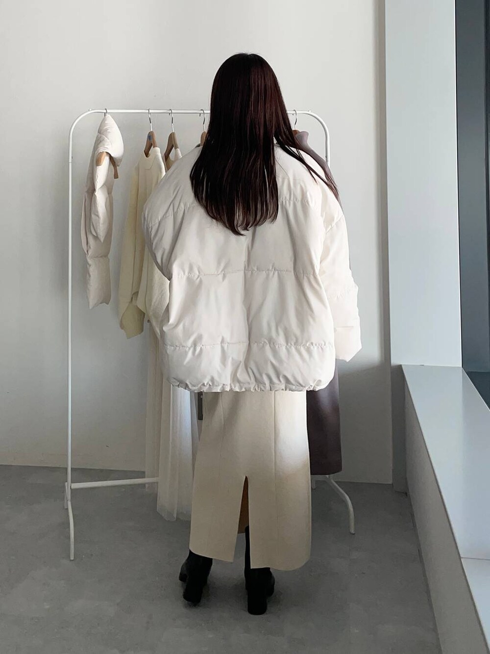 ブラック系のブーツ、ホワイト系のワンピース、グレー系のカーディガン/ボレロを着用したレディースの冬コーディネートの2枚目の写真